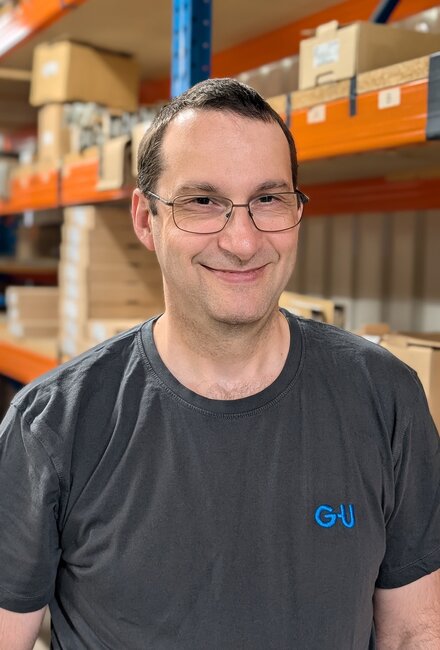 Mann mit GU-T-Shirt in Lager mit Kartons