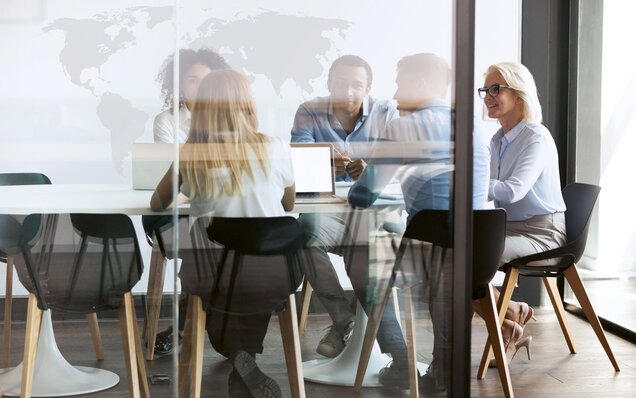 Fünf Personen bei Teammeeting am Tisch