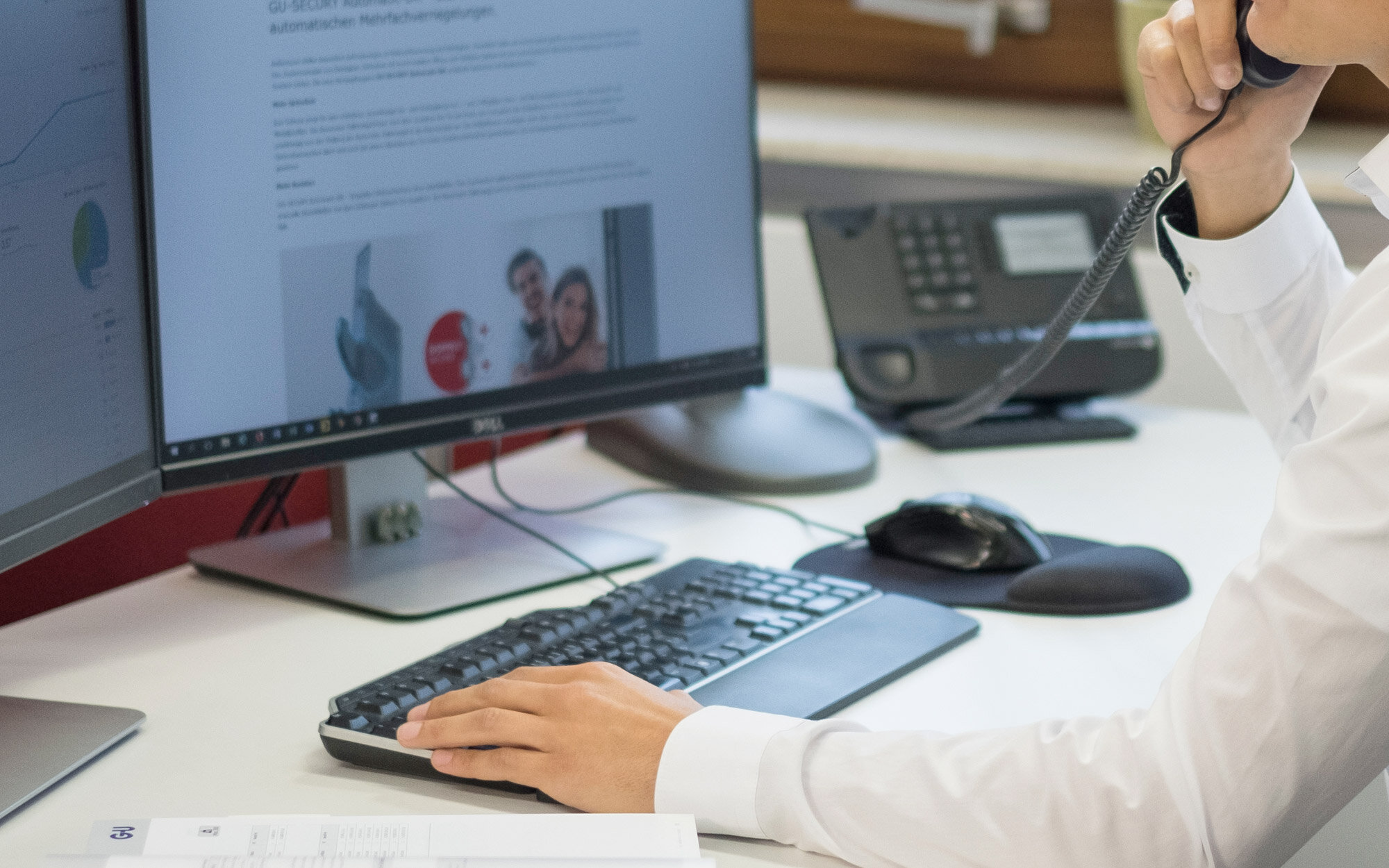 Mann arbeitet am PC mit Telefon