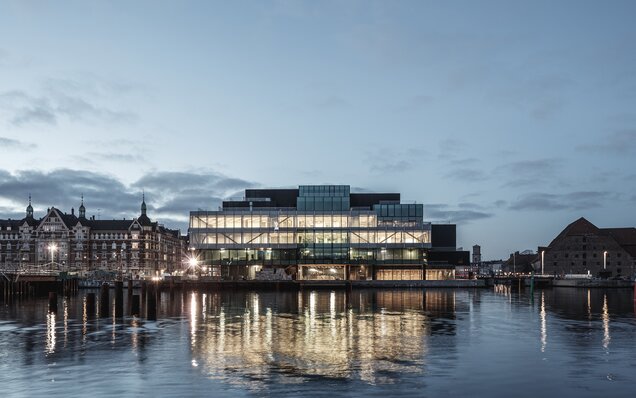 Освещённое здание у воды на закате