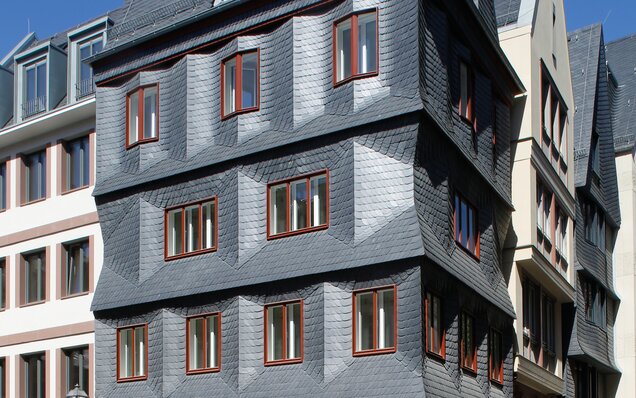 fachada con placas de pizarra y ventanas de madera