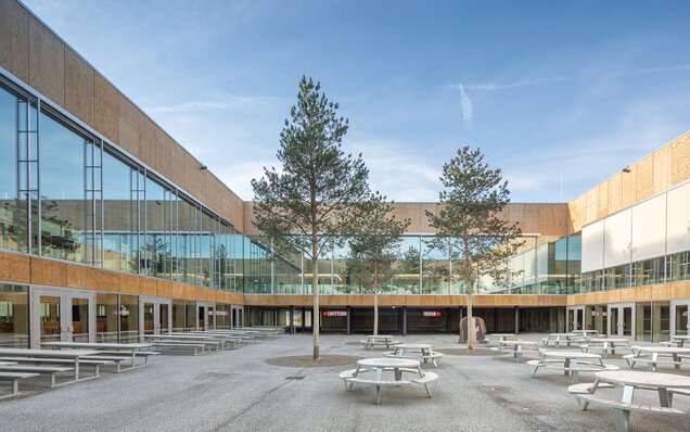 Oturma alanları ve ağaçlar bulunan avlu