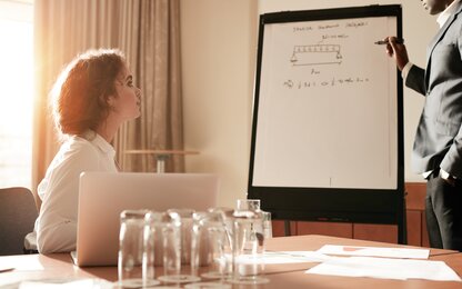 Business presentation with diagram on flipchart in meeting room